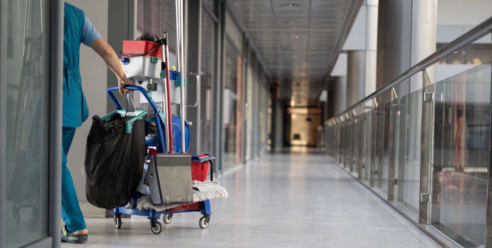 Un employé tire un chariot pour nettoyer les bureaux. Femme nettoyeur est engagé dans le travail.